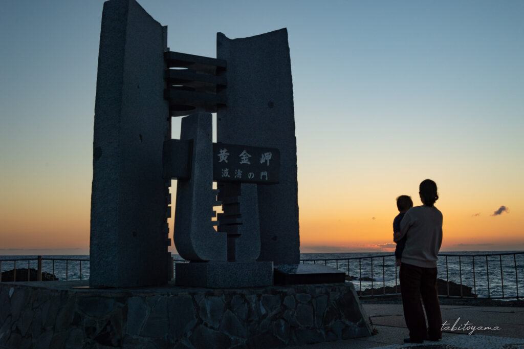 黄金岬にある波濤の門の隣で夕陽を眺めるパジャマ姿の妻と息子