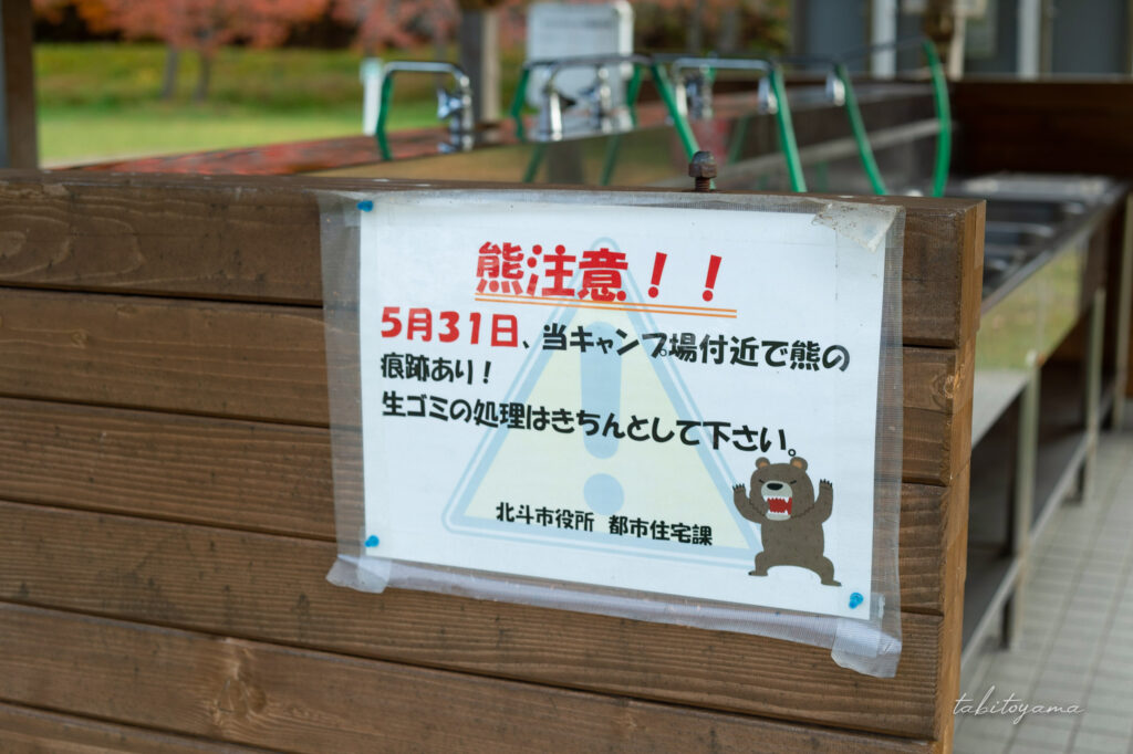 湯の沢水辺公園の炊事場にある熊注意の掲示物。キャンプ場付近で痕跡が見つかり、生ゴミの処理を徹底するよう書かれている。