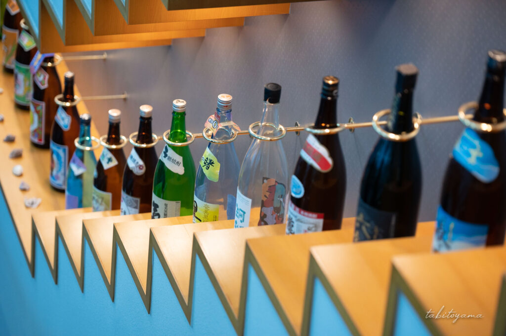 奄美空港エスカレーター脇に並ぶ地元焼酎瓶の数々