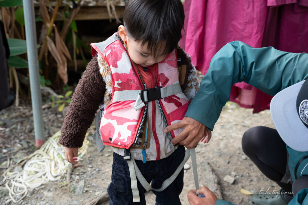 ガイドにライフジャケットを着せてもらう息子