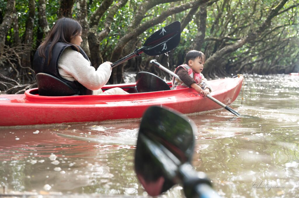 カヤックを漕ぐ妻と息子を眺める、手前には自分のパドルが映り込む