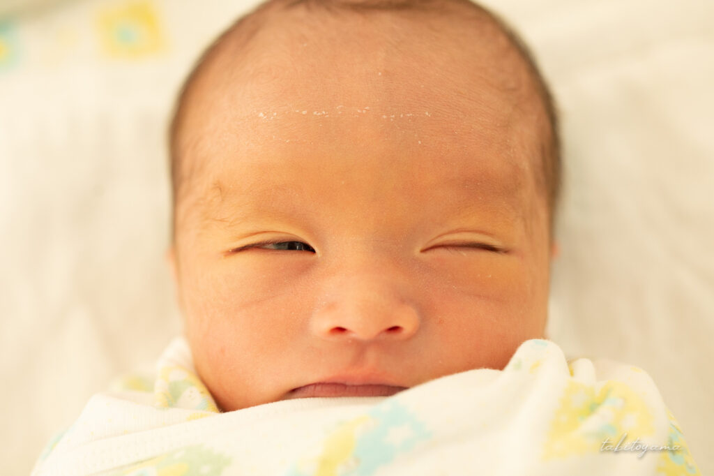 片目だけうっすらと開いた生後間もない息子