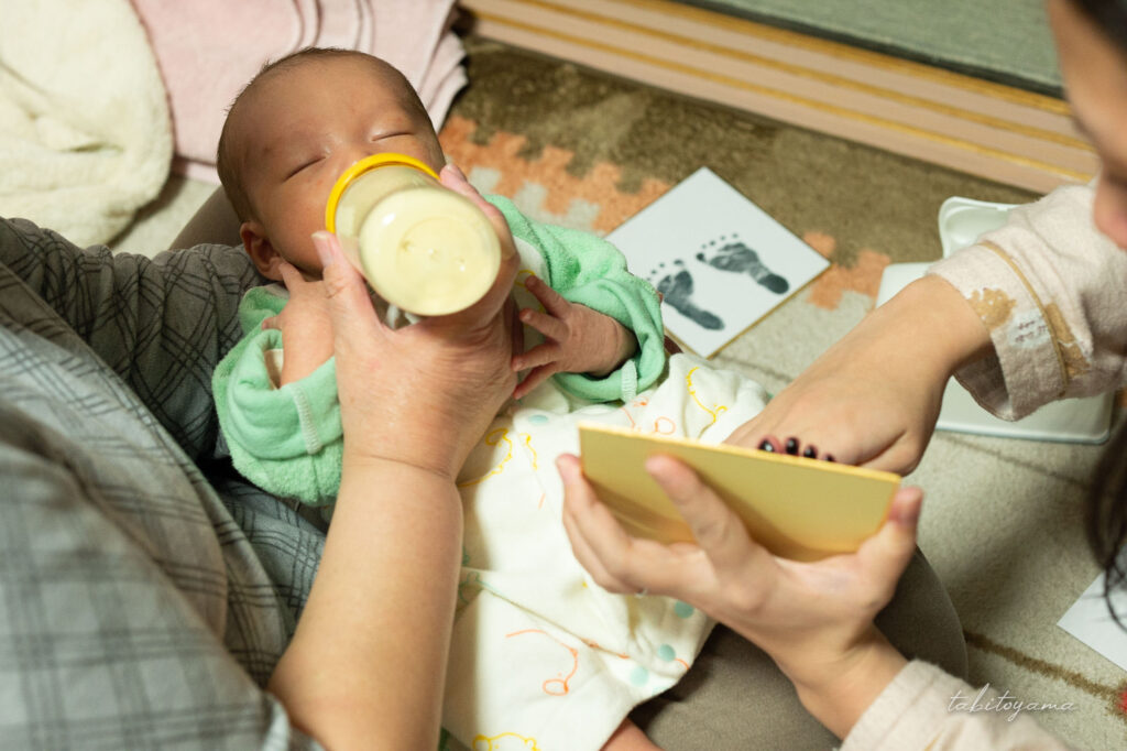 ミルクを飲みながら足形を取られる息子
