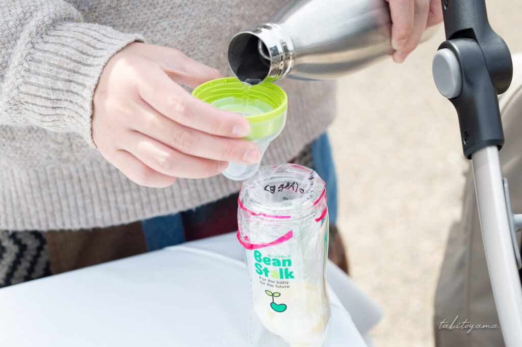 粉ミルク入りの哺乳瓶にお湯を注ぐ