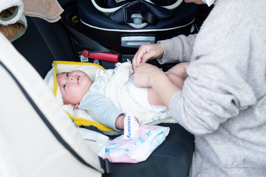 車の後部座席でおむつを交換される息子