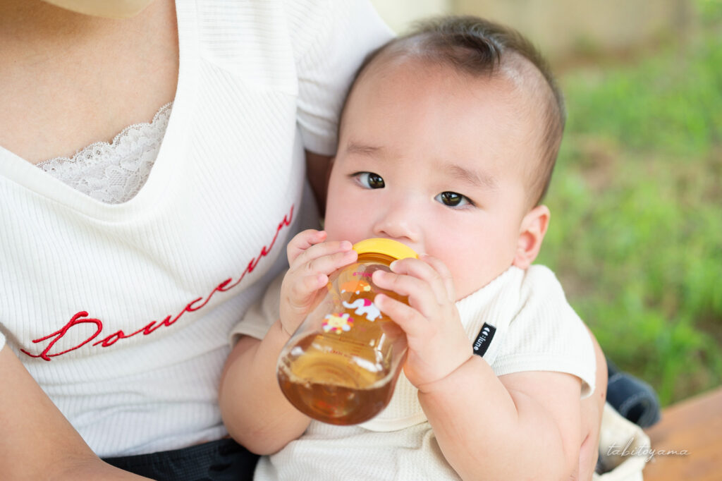 妻に抱かれながらベビー麦茶を飲む息子