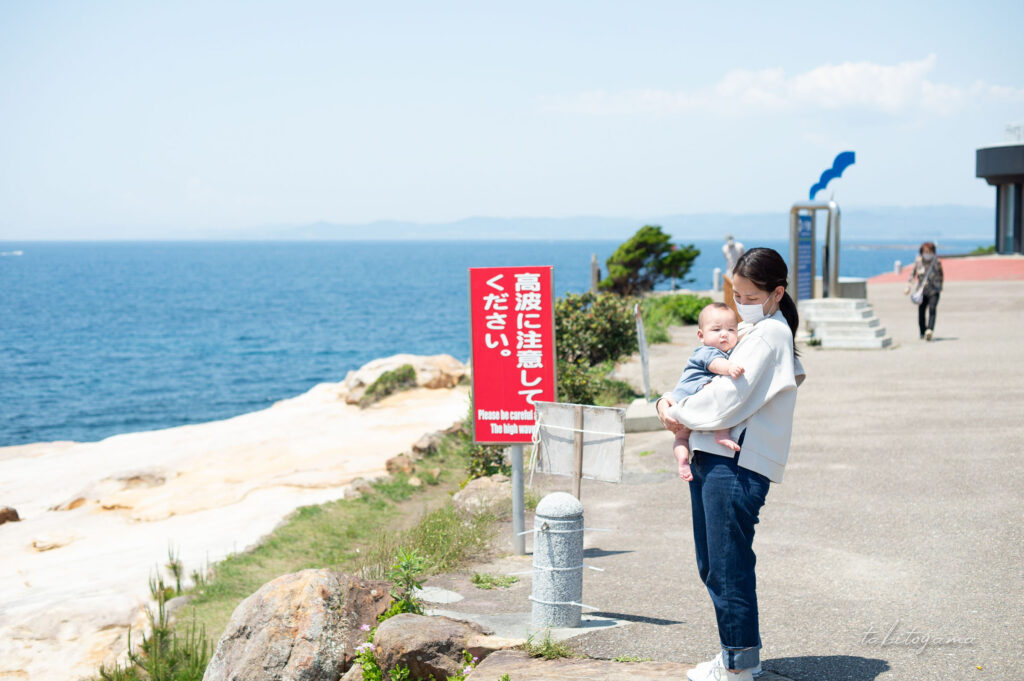 千畳敷の駐車場で海を背景に息子を抱き抱える妻