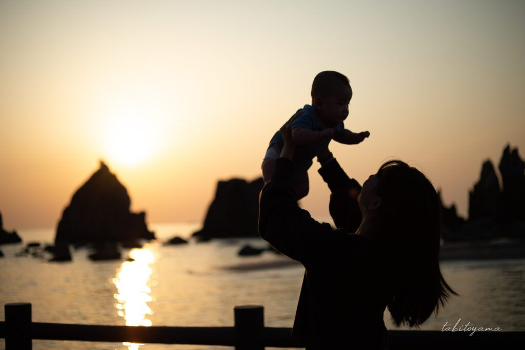 橋杭岩の朝日でシルエットになった抱き上げられた息子と妻