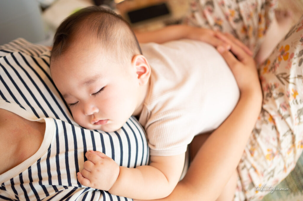 妻に抱えられながら眠る息子