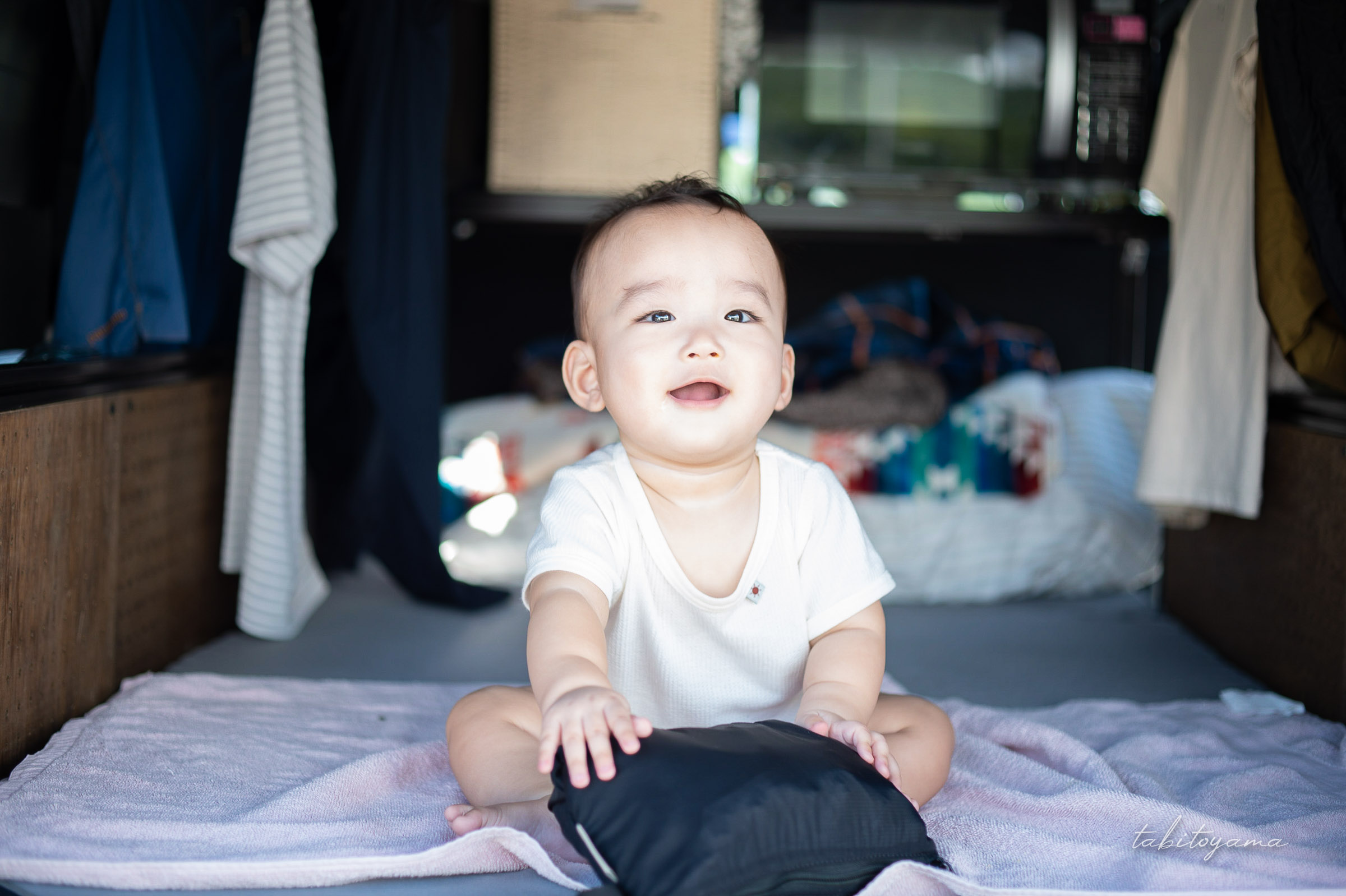 車中泊仕様に整えたハイエースの車内で座り、微笑む息子