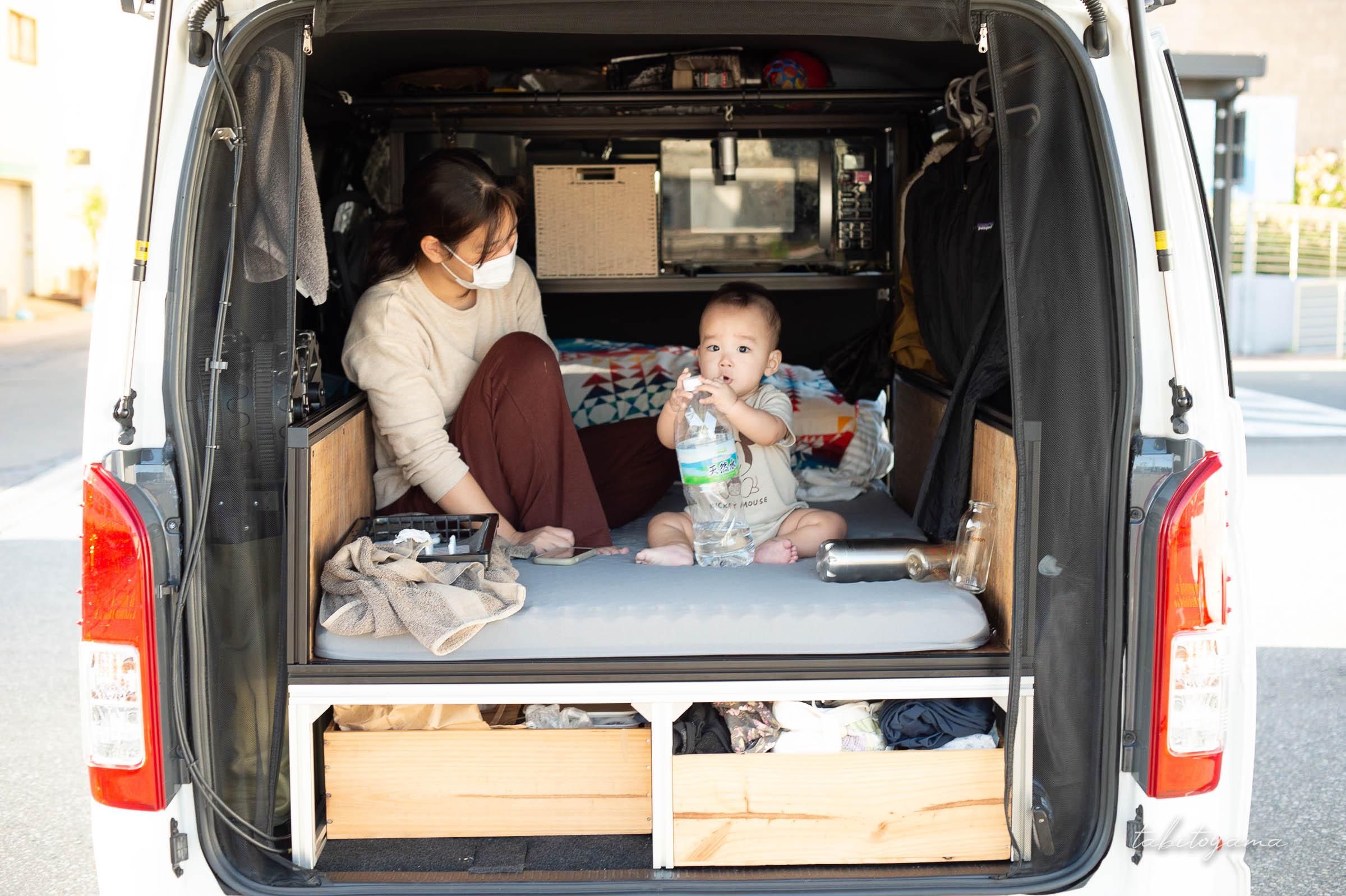 ハイエースの車中泊ベッドに座る妻と息子