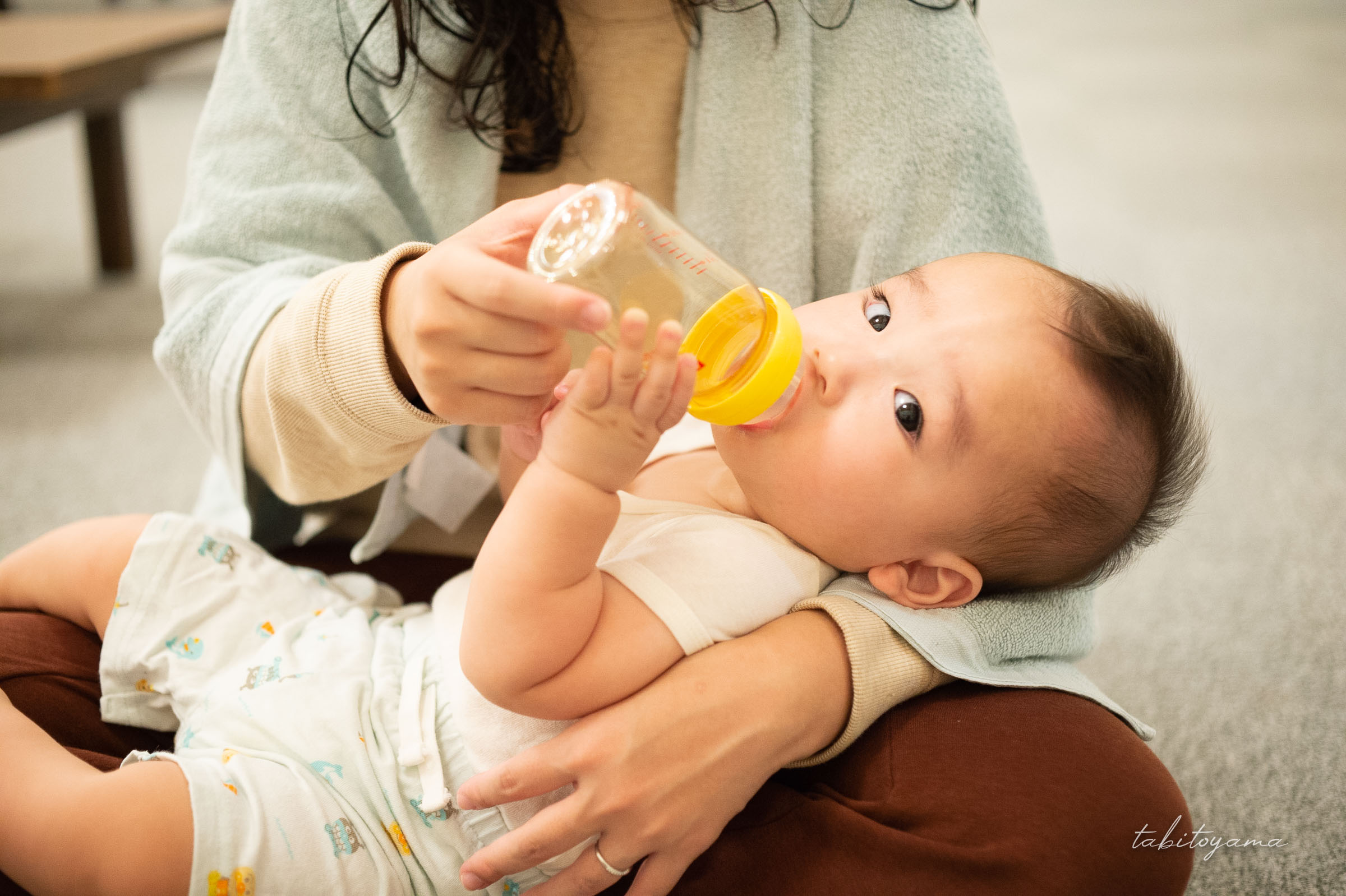 妻に抱き抱えながら入浴後にベビー麦茶を飲む息子
