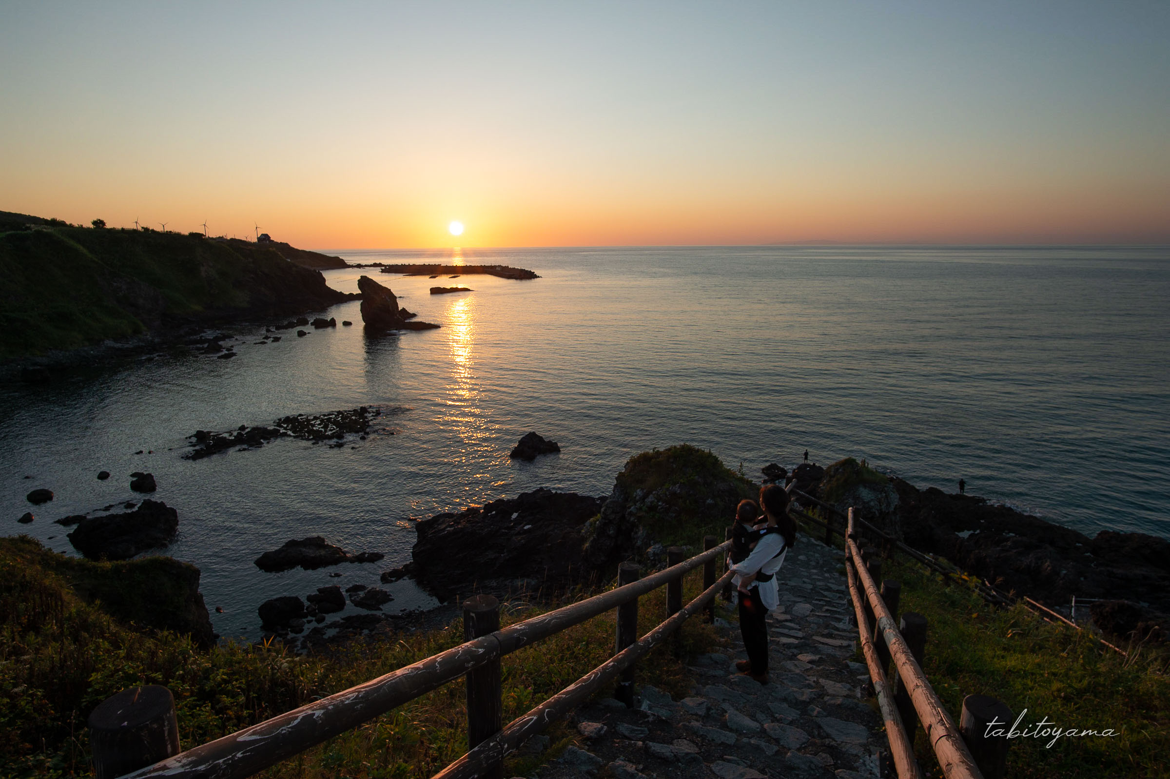 神の道から海に沈む夕陽を眺める妻と息子の後ろ姿