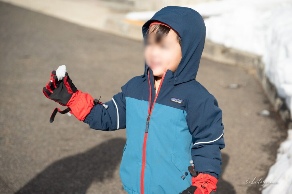 雪の塊を手に嬉しそうな笑顔の息子