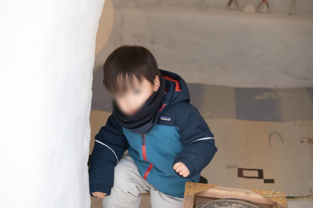 かまくらの中から立ちあがろうとする息子