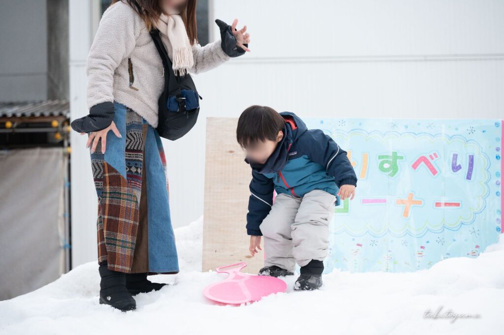 そりすべりコーナーで遊ぶ妻と息子