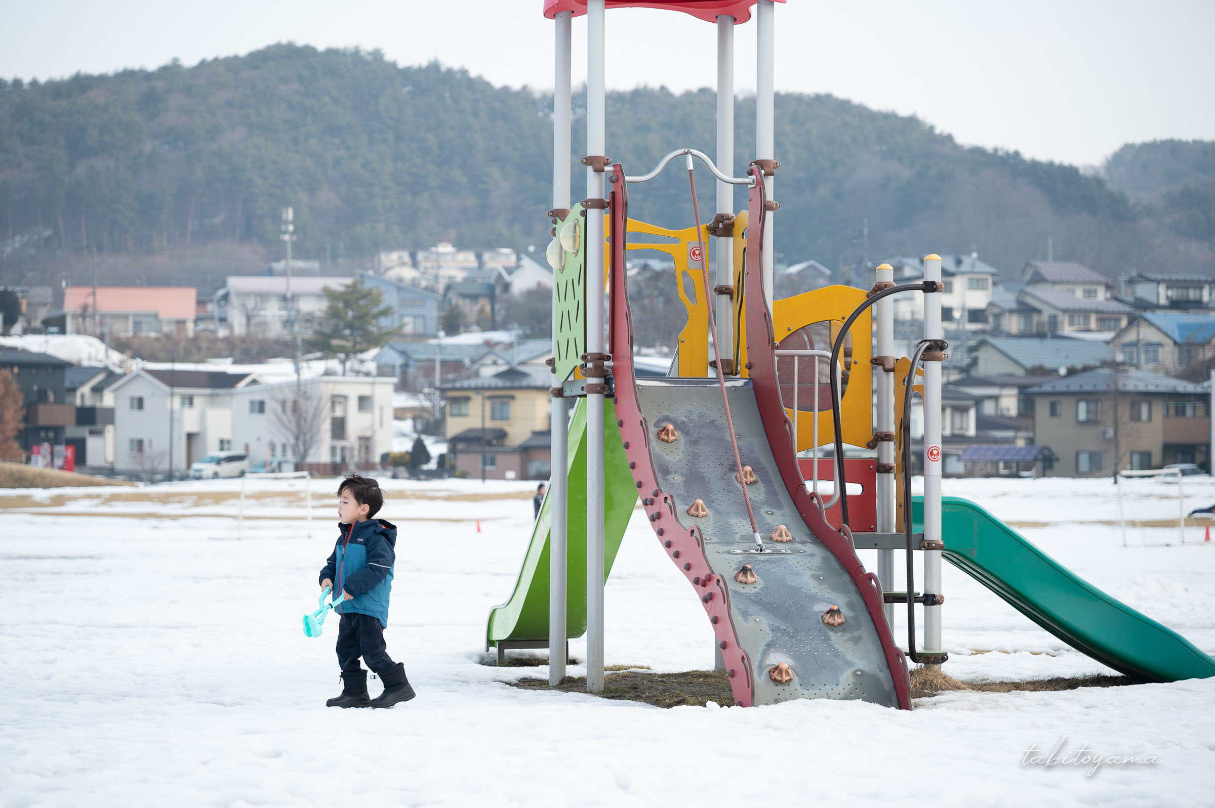 雪が積もった高松公園の遊具と息子