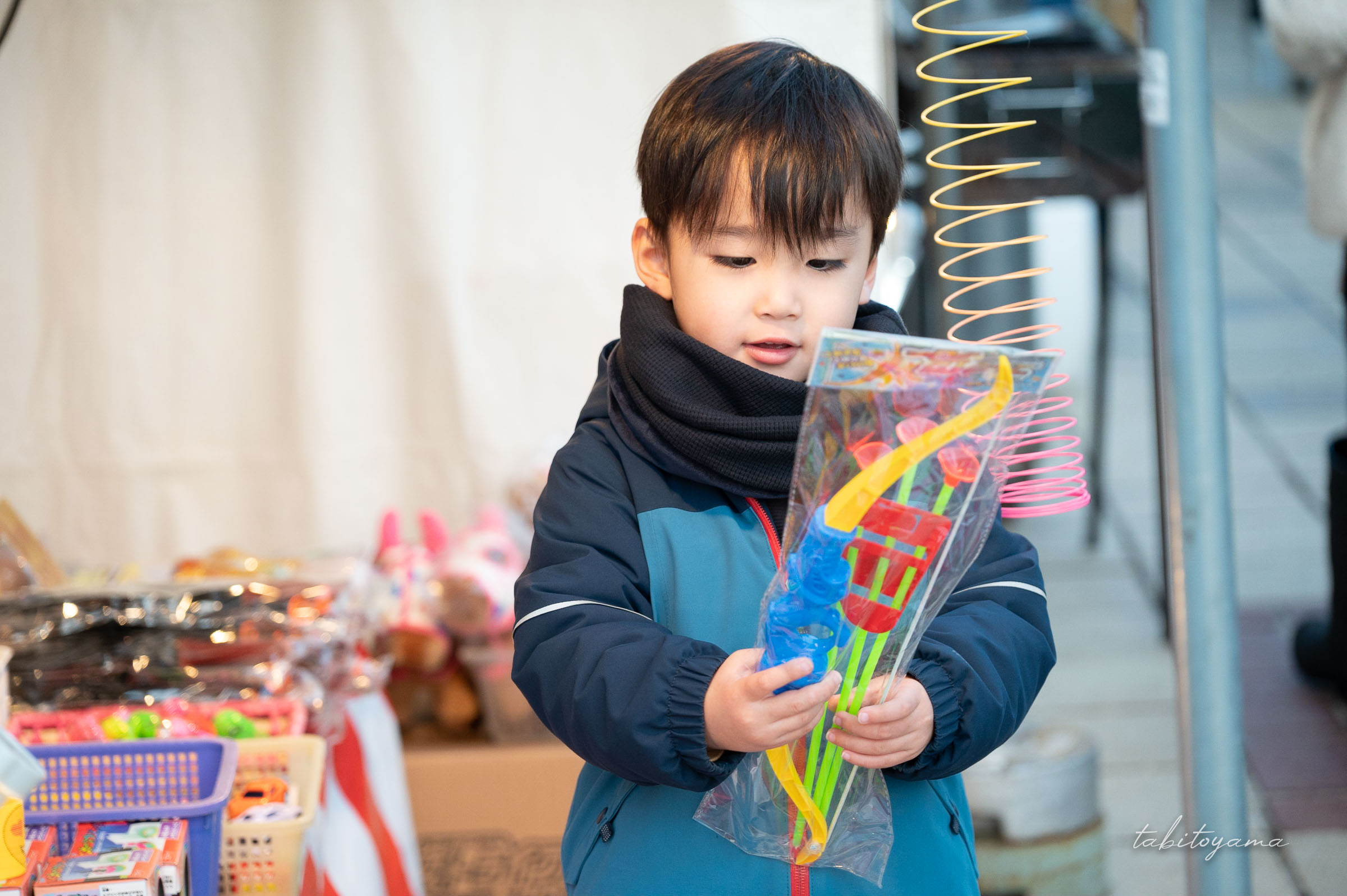 出店のおもちゃを眺めながら嬉しそうな表情の息子