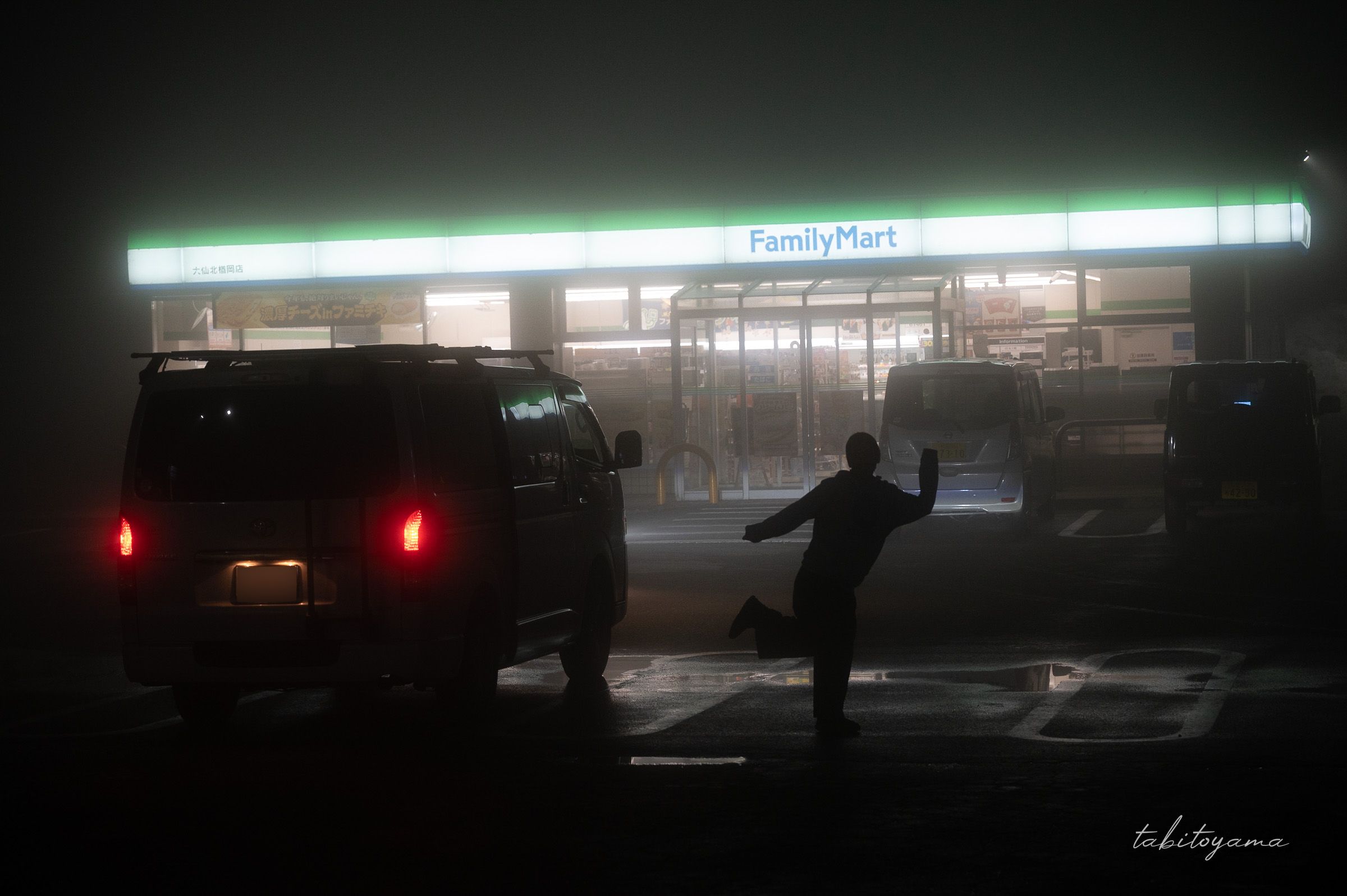 霧に包まれたコンビニをバッグにポーズをとる妻のシルエット