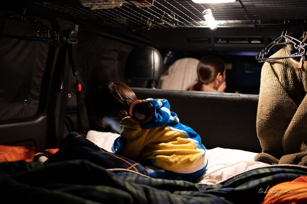 ランタンに照らされる車内で過ごす妻と息子