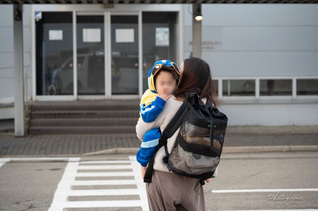 妻に抱えられながらフェリーターミナルへ向かう眠そうな息子