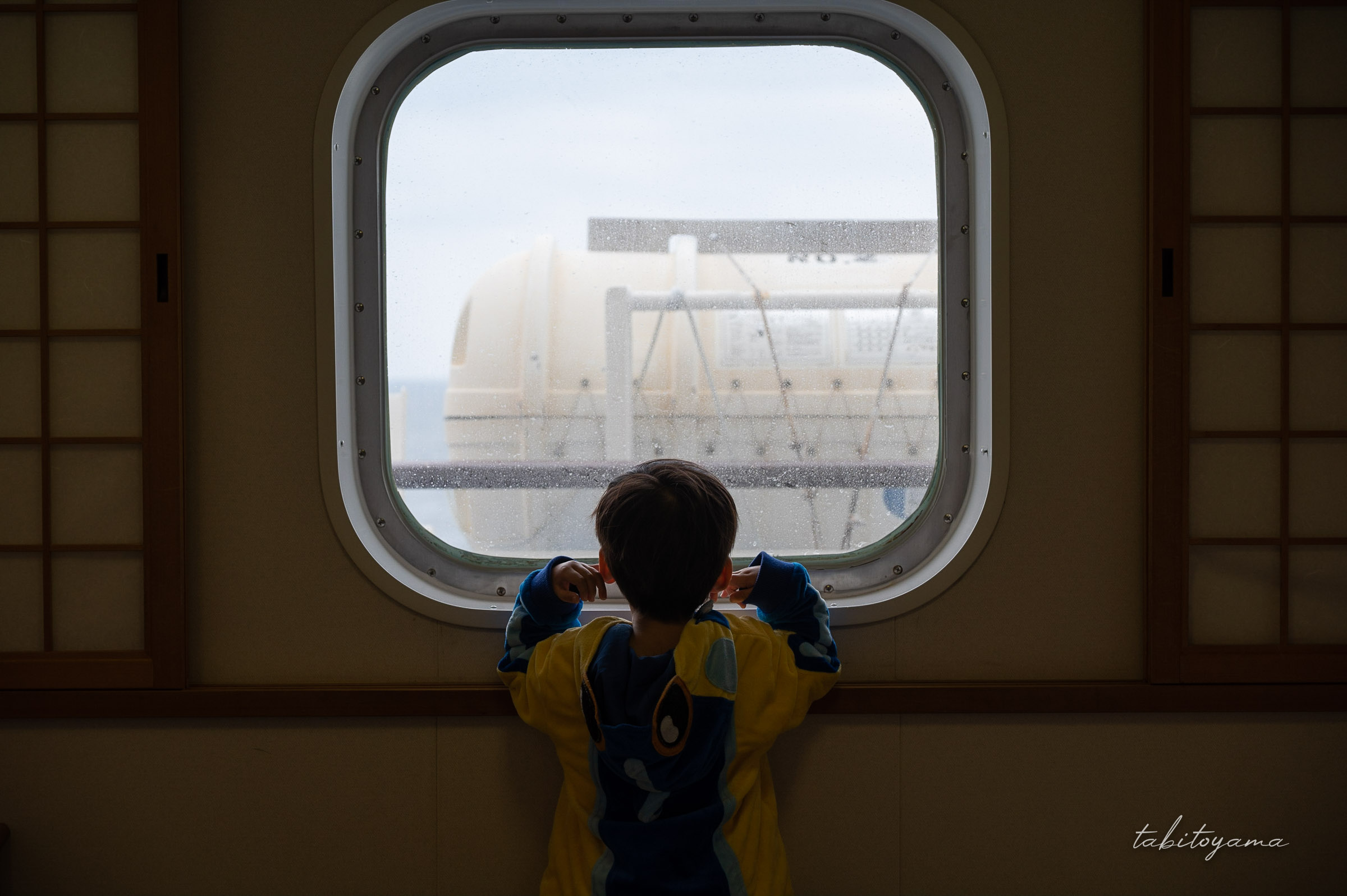 フェリー個室の窓から外を眺める息子