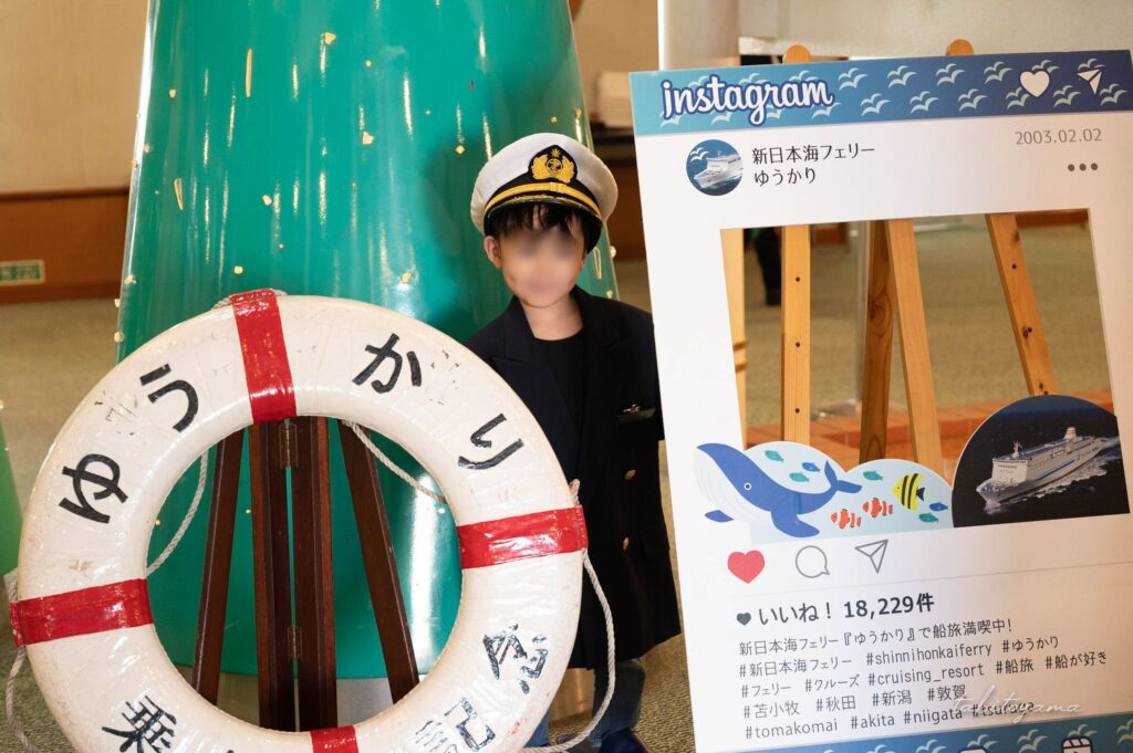 貸し出し用の帽子と制服を身に付けゆうかり乗船の記念撮影をする息子