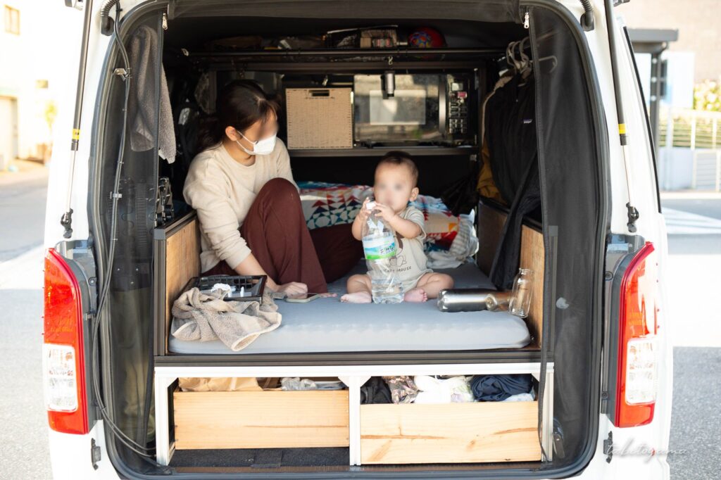 ハイエースの車中泊ベッドに座る妻と息子