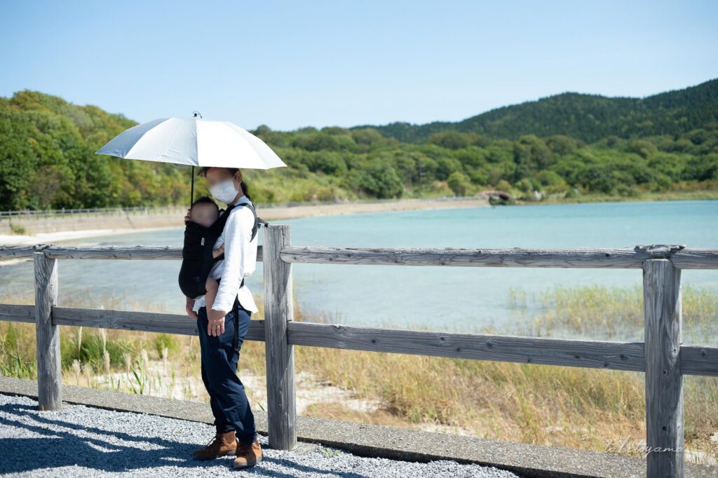 宇曽利湖の前で日傘を差してカメラ目線の妻と息子