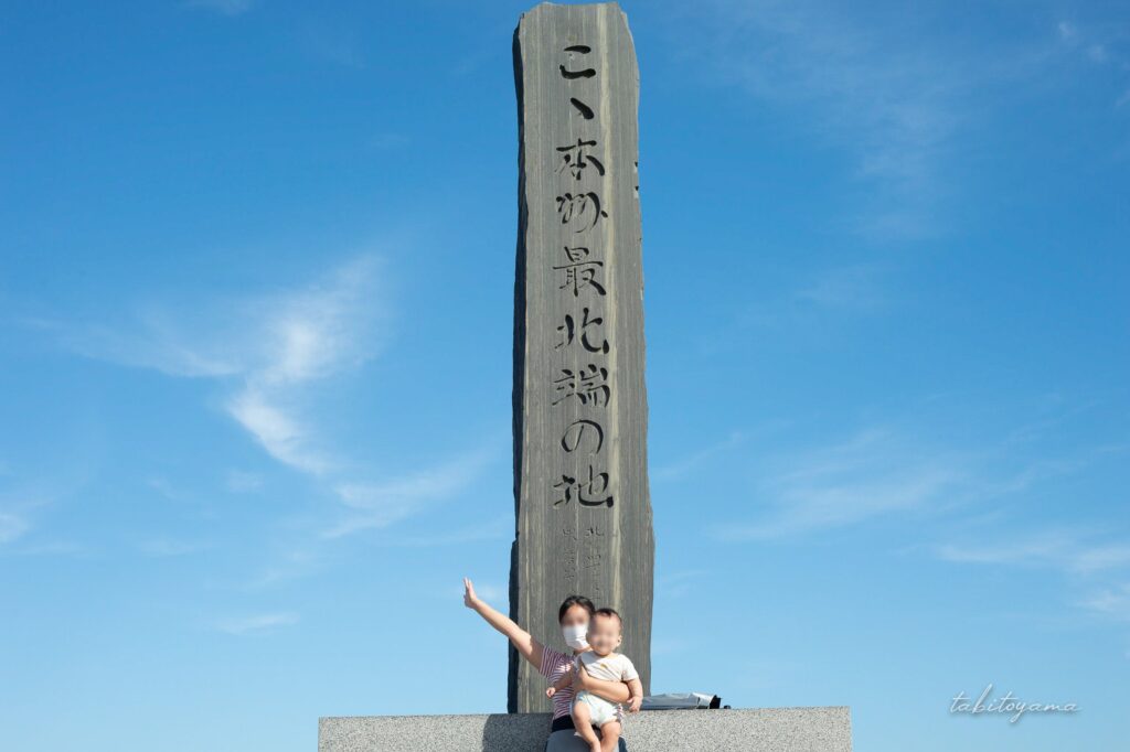 青空と本州最北端の碑の前で笑顔の妻と息子
