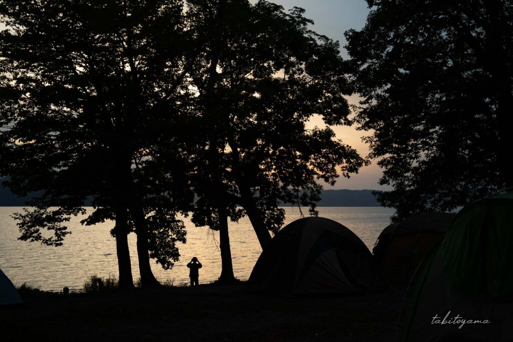 仲洞爺キャンプ場から夕暮れを眺める人とテントのシルエット