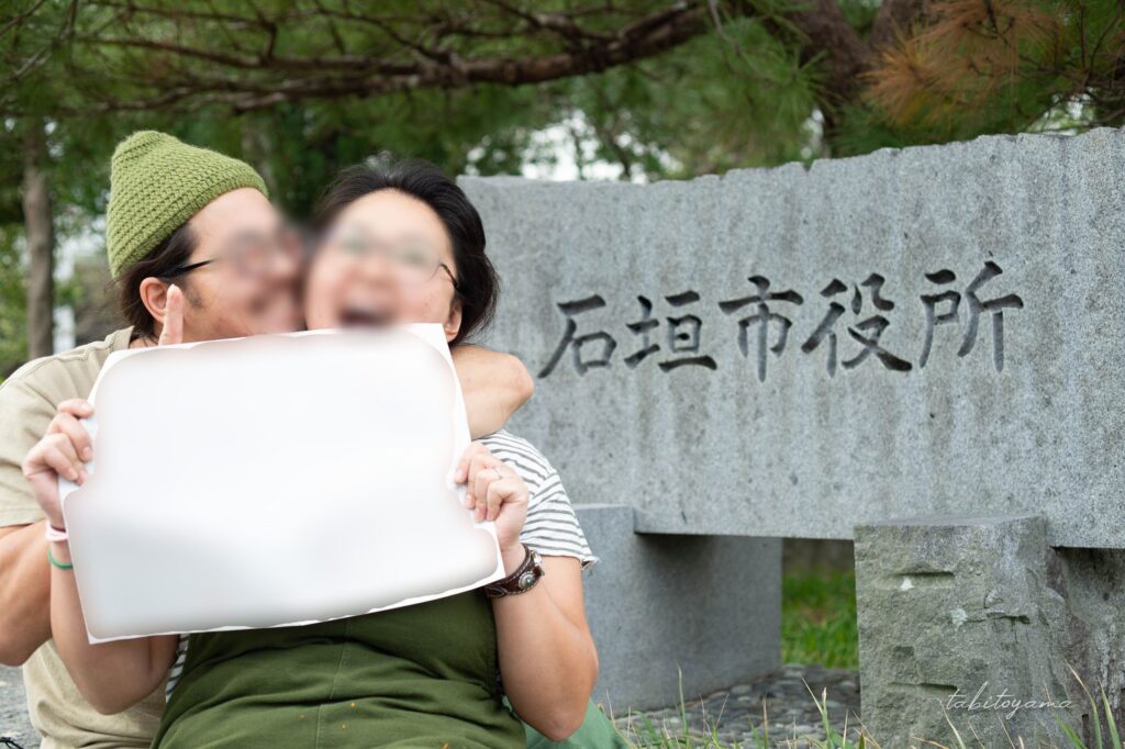 石垣市役所前で婚姻届を手に嬉しそうな表情の友人夫婦