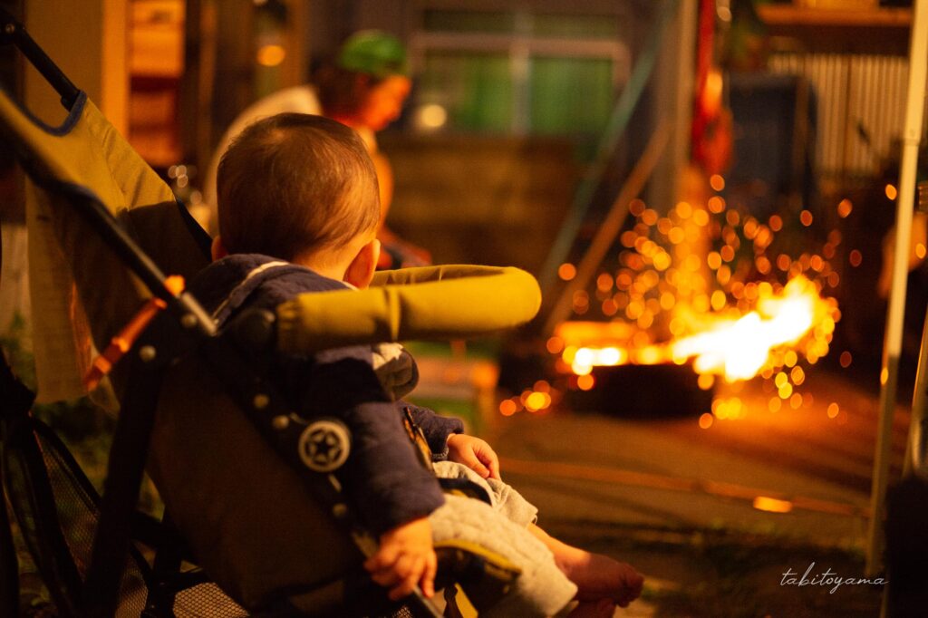 友人宅の庭で火おこしをする様子を眺める息子