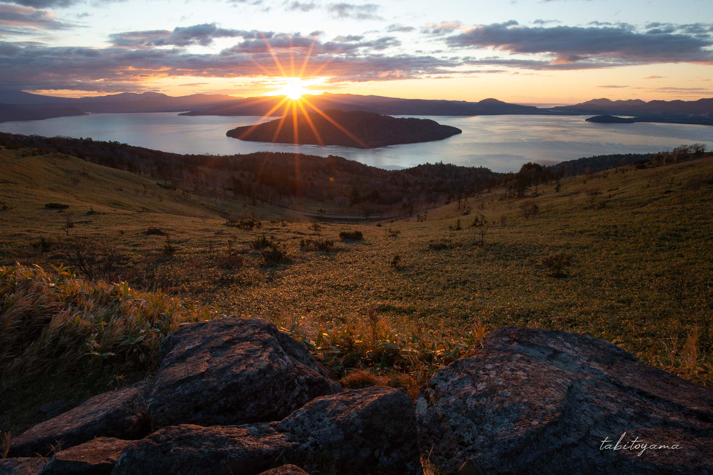 美幌峠から眺める日の出、手前の岩場や笹藪が赤く照らされる