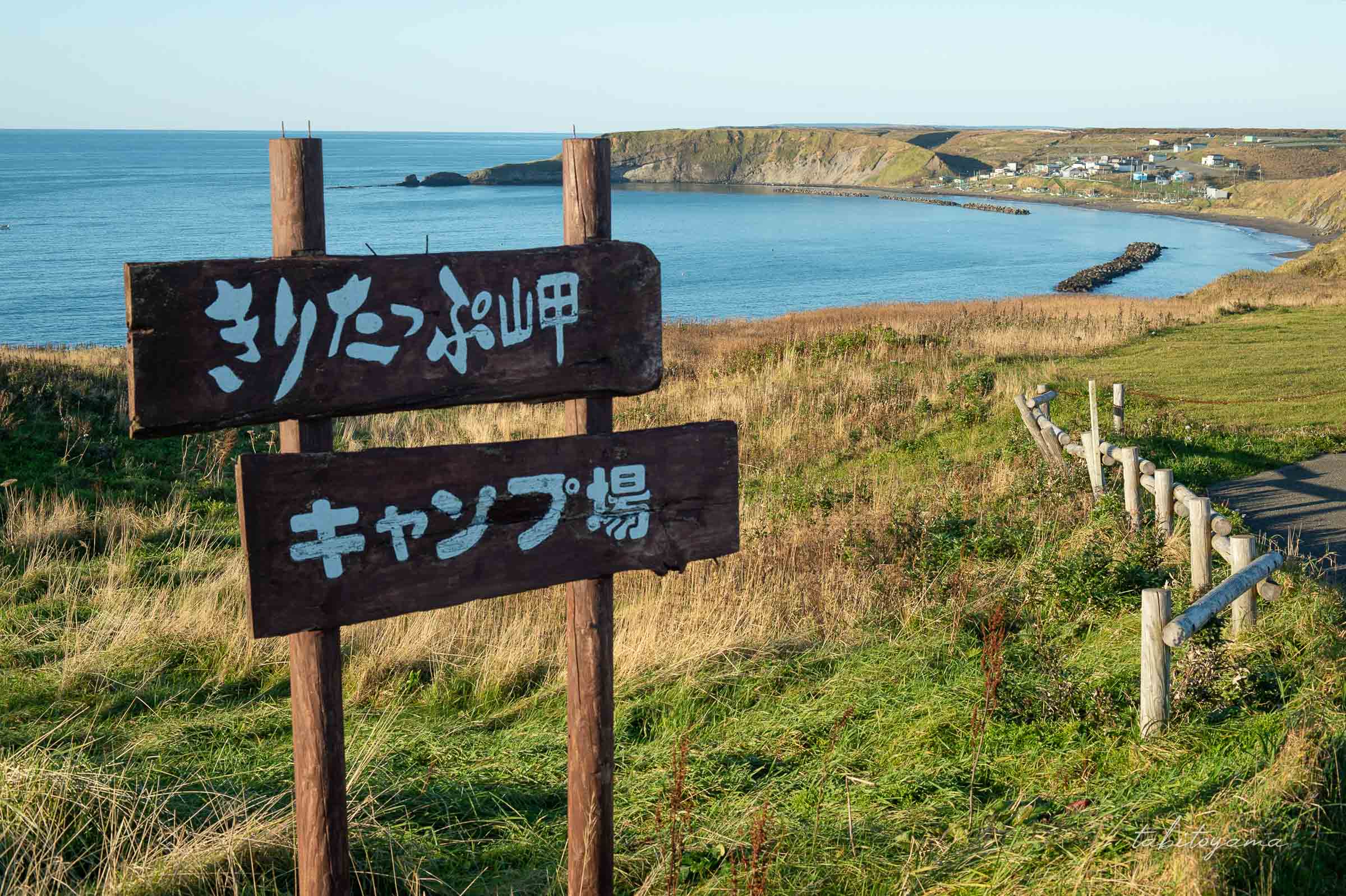きりたっぷ岬キャンプ場の看板、背景は周辺の入江