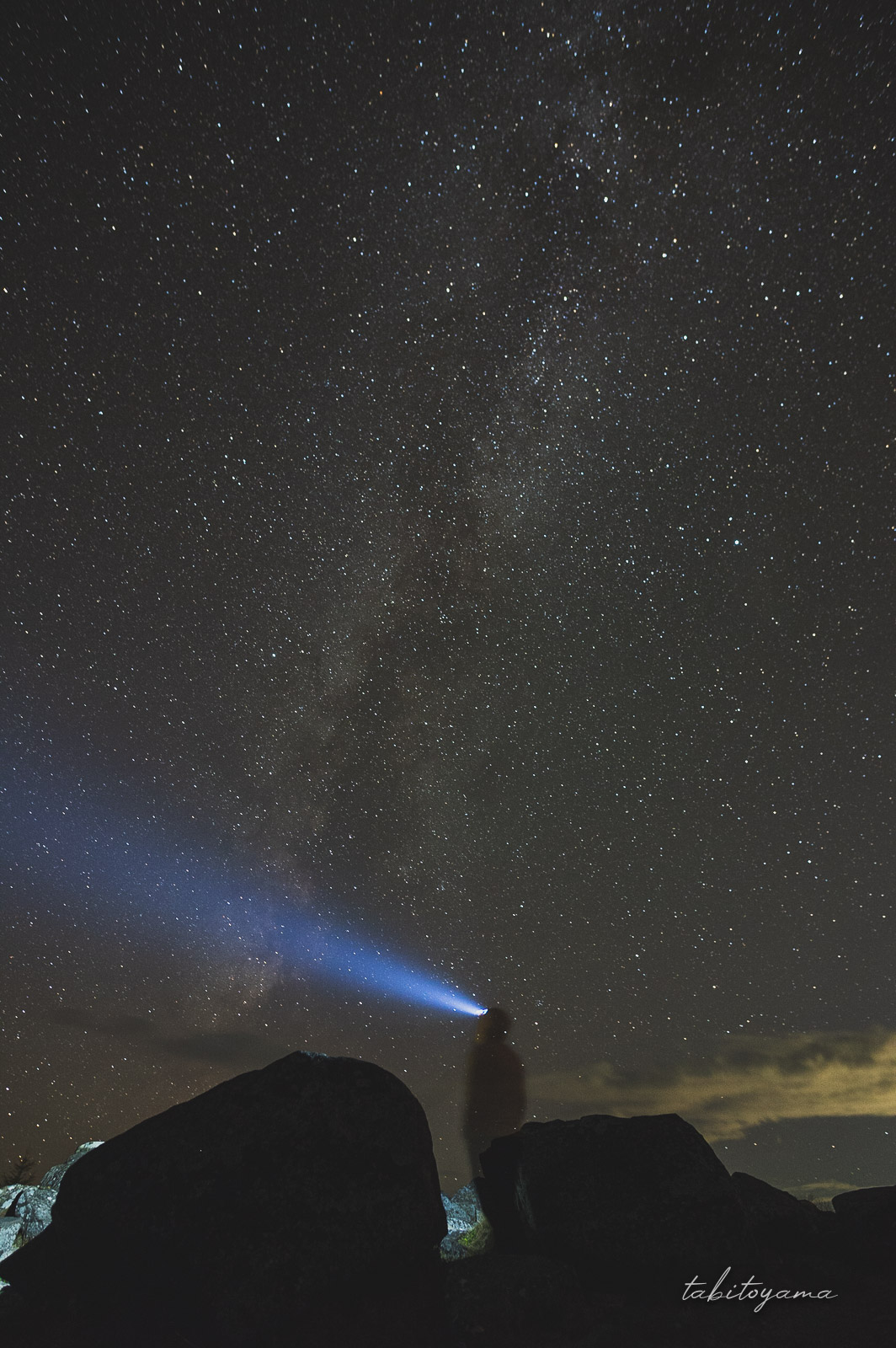 美幌峠の天の川を見上げる人影、ヘッドライトの光線が伸びる