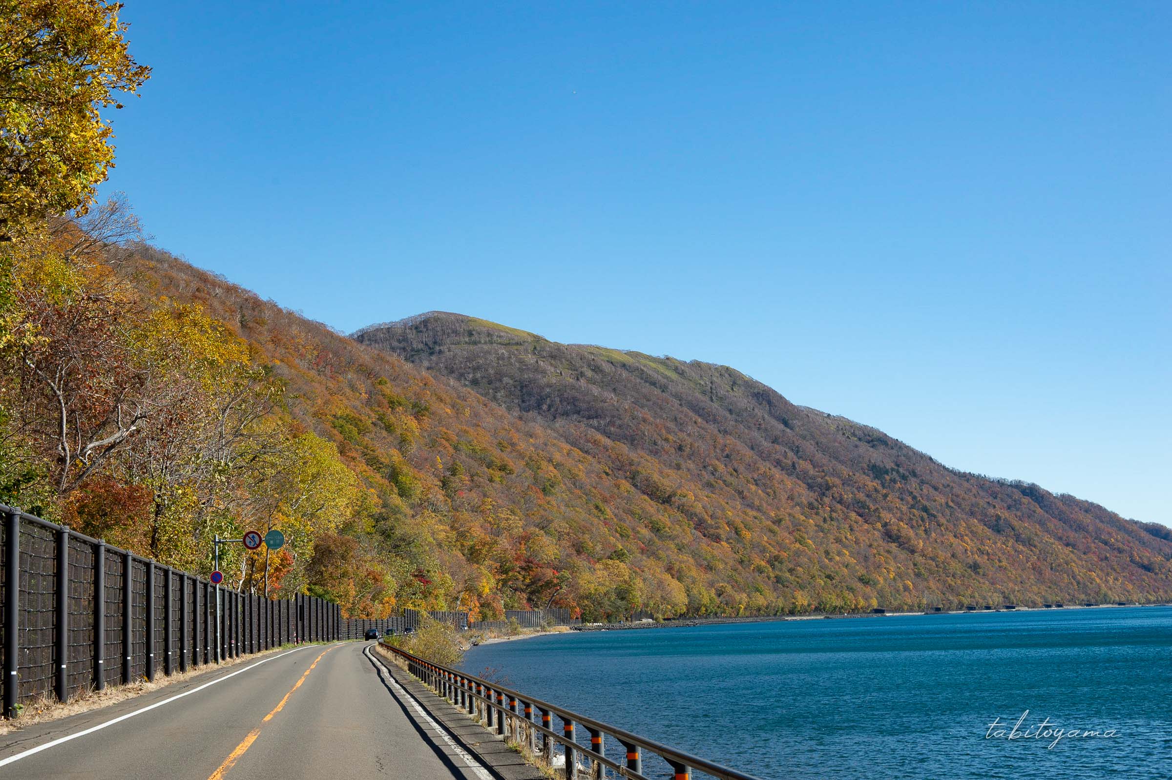 支笏湖畔沿いの道路、紅葉に色づく山と青い空