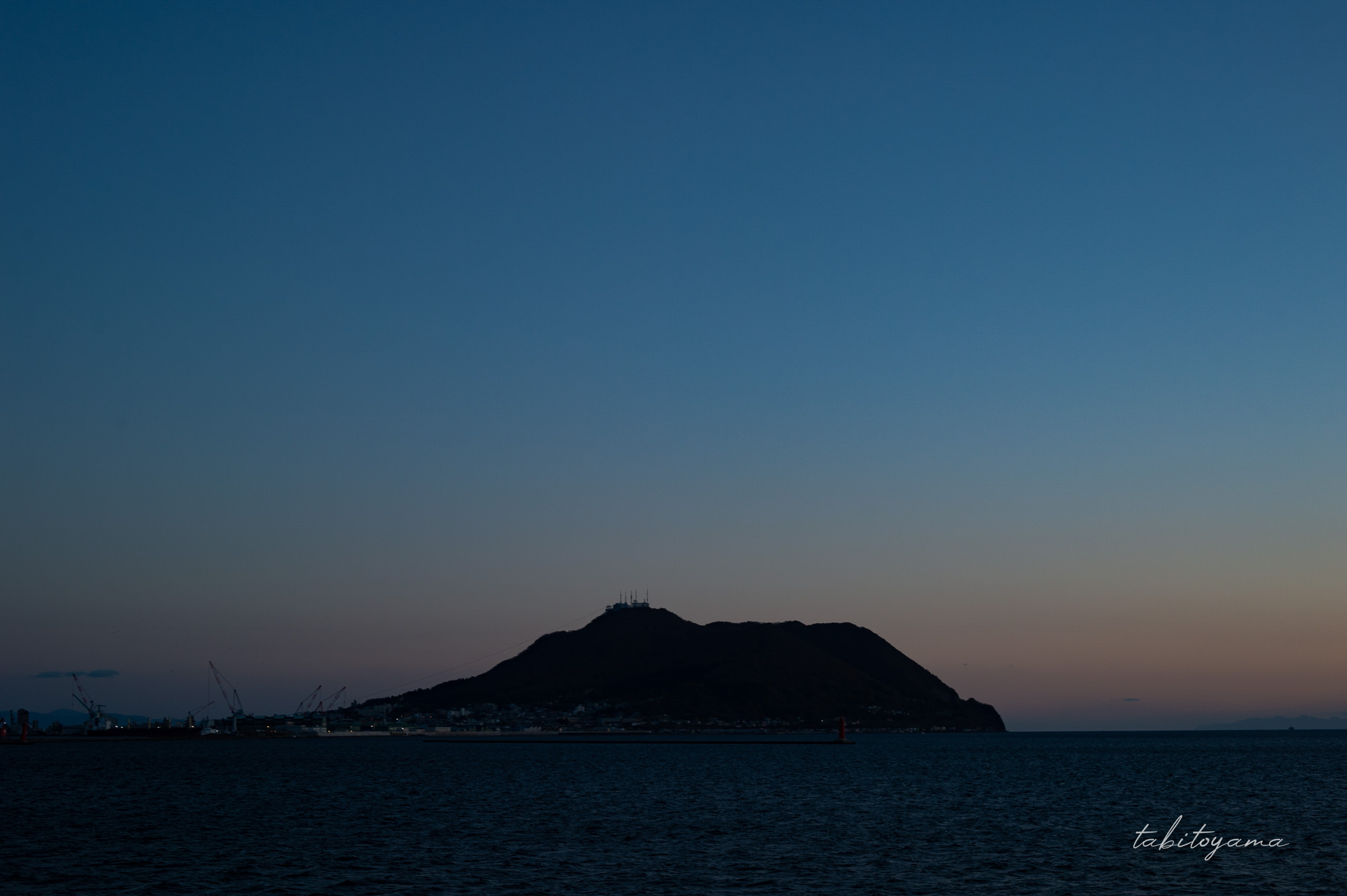 大間行きフェリーの船上デッキから眺める、日没後の空と函館山のシルエット