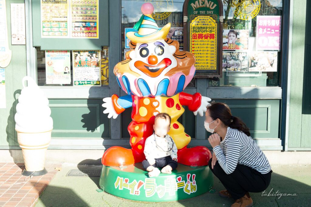 ラッキーピエロの店舗前に設置されている、ラッキーくんと記念撮影する妻と息子