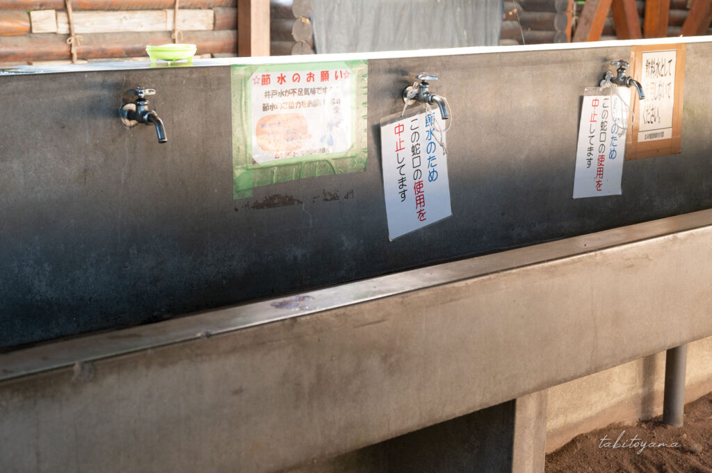 上磯ダム公園キャンプ場の炊事棟内にある蛇口。一部使用中止され、そばには節水のお願いが掲示されている。