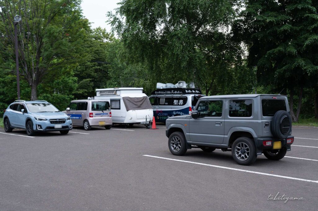 柏木地区レクリエーション施設の駐車場に停まる車両。奥にはキリスト教の街宣車。