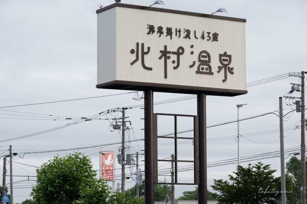 北村温泉ホテル敷地内にある大型看板。奥には向かい側にあるセイコーマートの看板が見える。