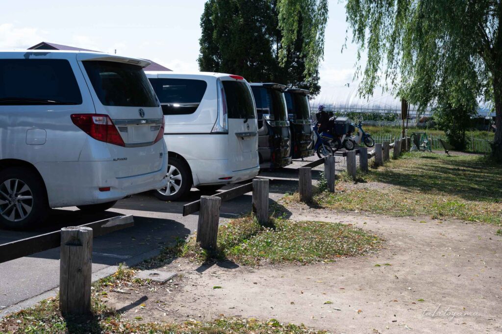 北村中央公園ふれあい広場キャンプ場の駐車場。車とバイクがずらりと並んでいる。
