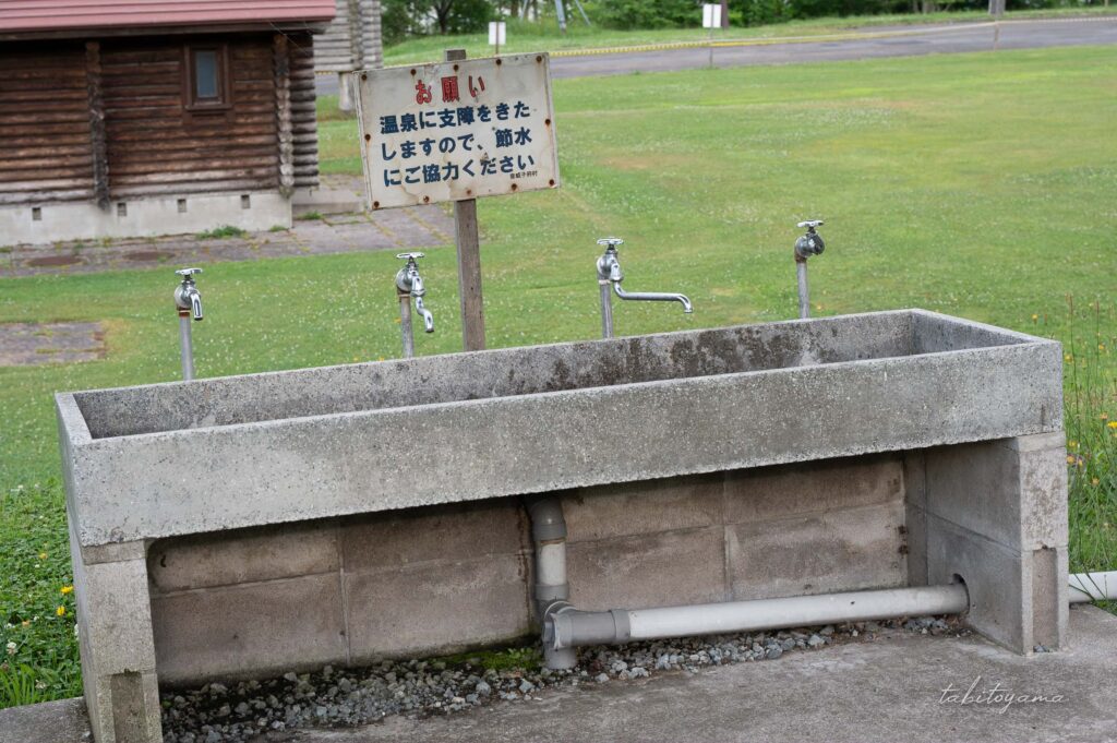 天塩川リバーサイドパークキャンプ場の洗い場。奥には節水の協力を促す看板がある。