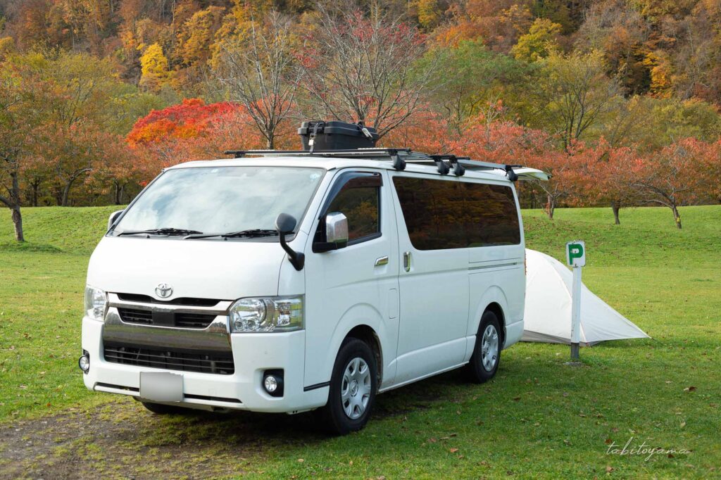 湯の沢水辺公園のオートサイト。Pマーク看板そばに駐車したハイエース。