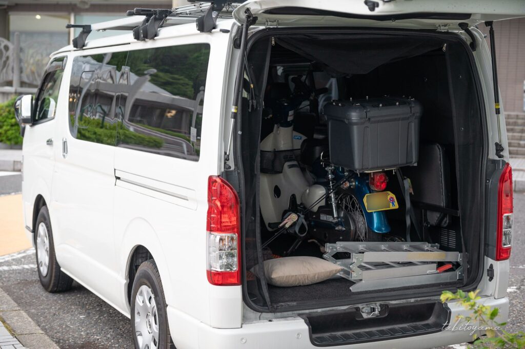 ハイエースの荷室に積載されたリトルカブと折り畳まれた積み込み用のラダー