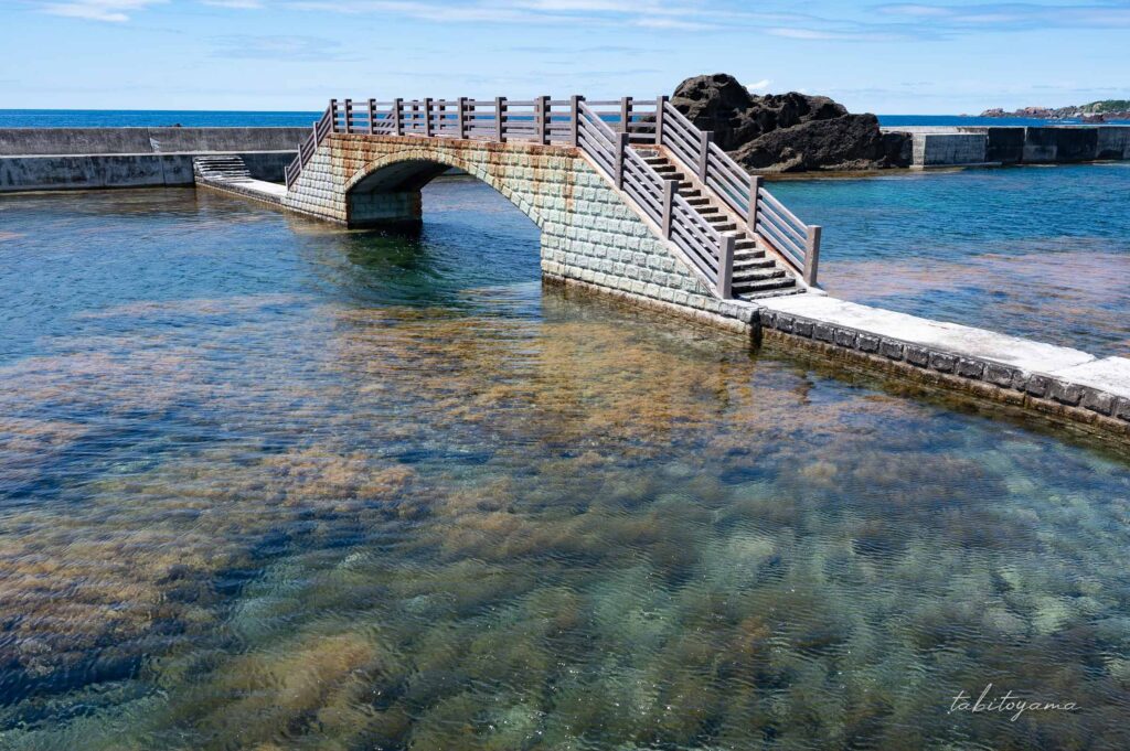 佐渡ヶ島の千畳敷にある海にかかる橋、周りには透き通った海が広がっている