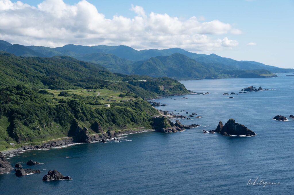 大野亀頂上から眺める景色、海と緑豊かな大地と湾岸沿いの道路が見える