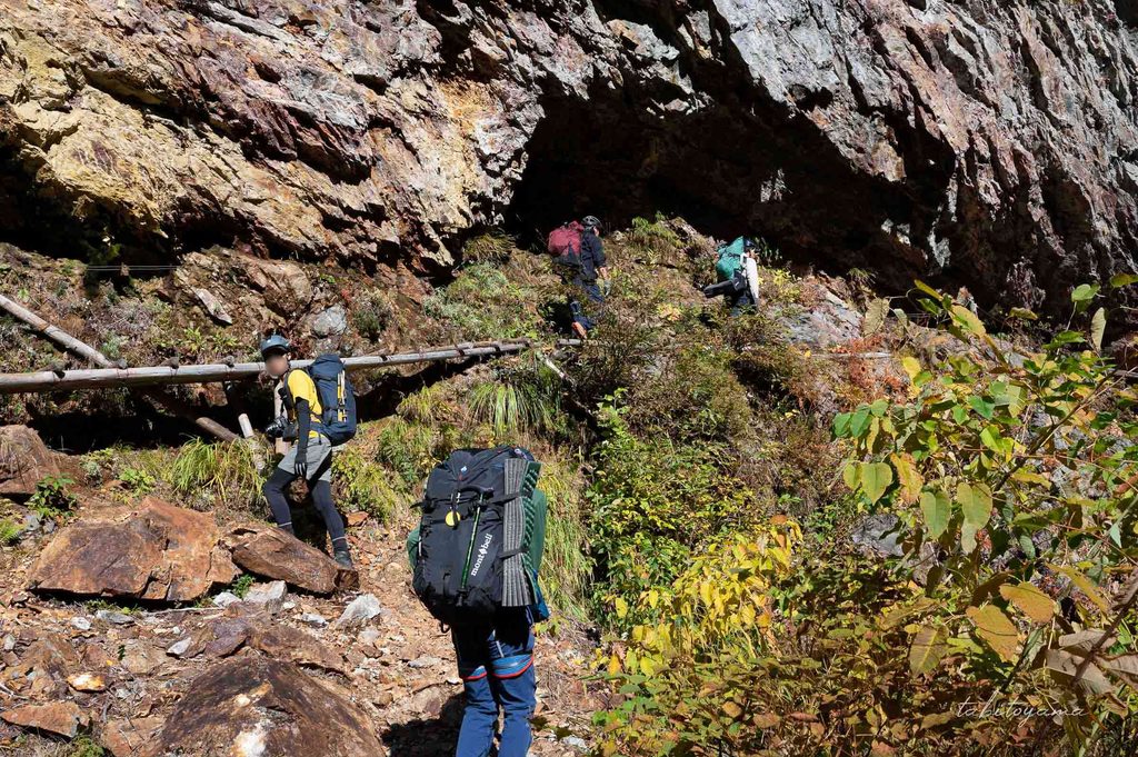 くり抜いたような岩肌を歩く登山者