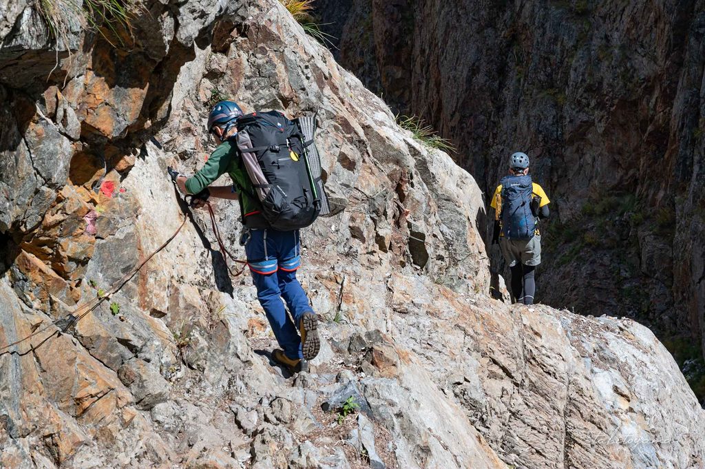 岩肌に設置された番線を掴みながら身長に歩く登山者